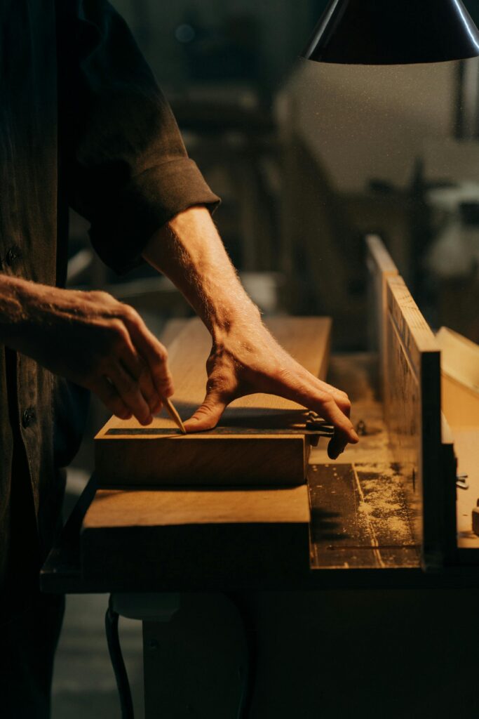 pexels-photo-5089178-5089178 A craftsman skillfully sanding a wooden plank in a well-lit workshop.